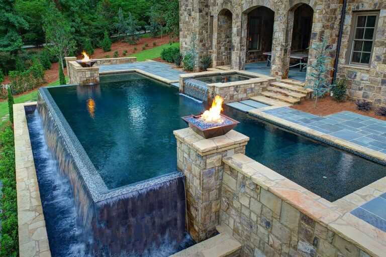 photo of a backyard waterfall pool design in PebbleTec Black Marble Pool Finish dark blue water color with lightstreams tile features and fire bowls by Thrasher Pools & Spa submitted for World's Greatest Pools 2016