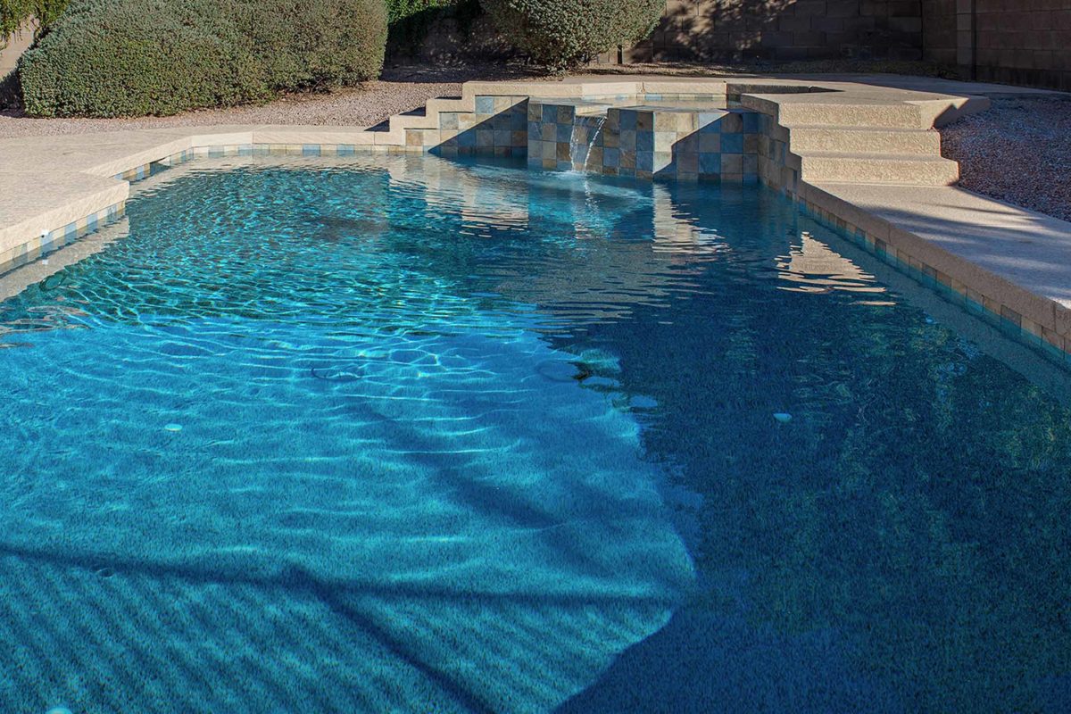photo of a backyard pool design in PebbleTec Blue Wave Pool Finish with a Jacuzzi waterfall feature