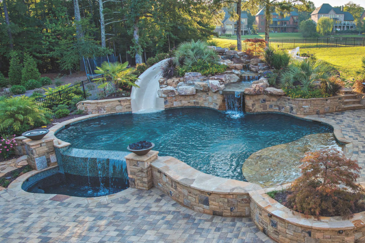 photo of a backyard round pool design with a waterslide, waterfall jacuzzi feature in PebbleTec Black Marble Pool Finish medium blue water color