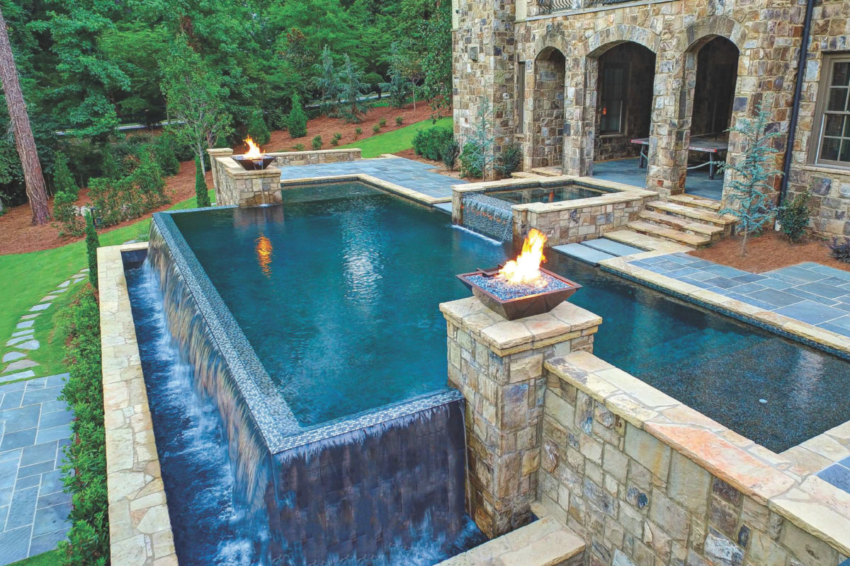 photo of a waterfall edge pool in PebbleTec Black Marble Pool Finish medium blue water color with fire bowl features and lightstreams tile embellishments