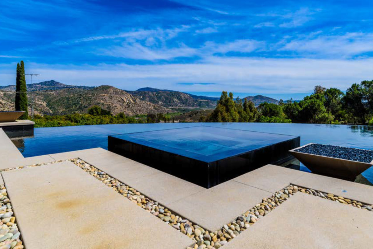 photo of a waterfall edge pool in PebbleTec Black Pearl Pool Finish dark blue water color with a jacuzzi and Mountain View with fire bowl features