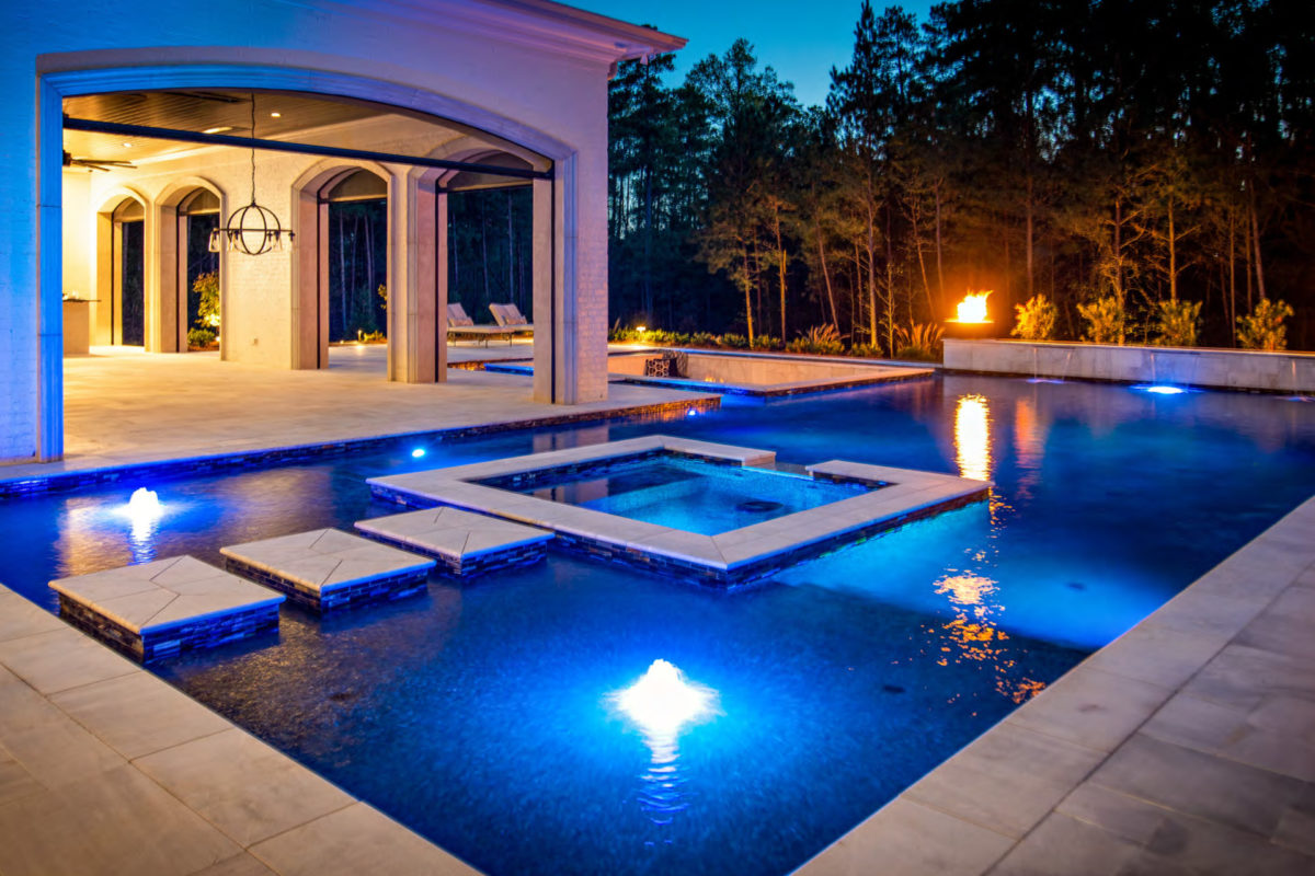 photo of a backyard pool and jacuzzi design in PebbleTec Black Pearl Pool Finish dark blue water color at sunset with a fire bowl feature
