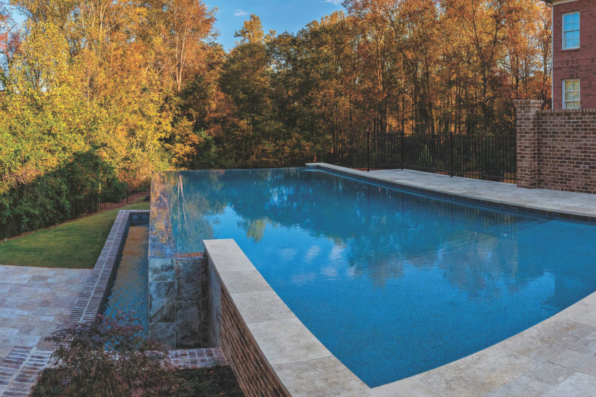 photo of a backyard pool design in the fall in PebbleTec Blue Lagoon Pool Finish medium blue water color with a waterfall feature for World's Greatest Pools 2016
