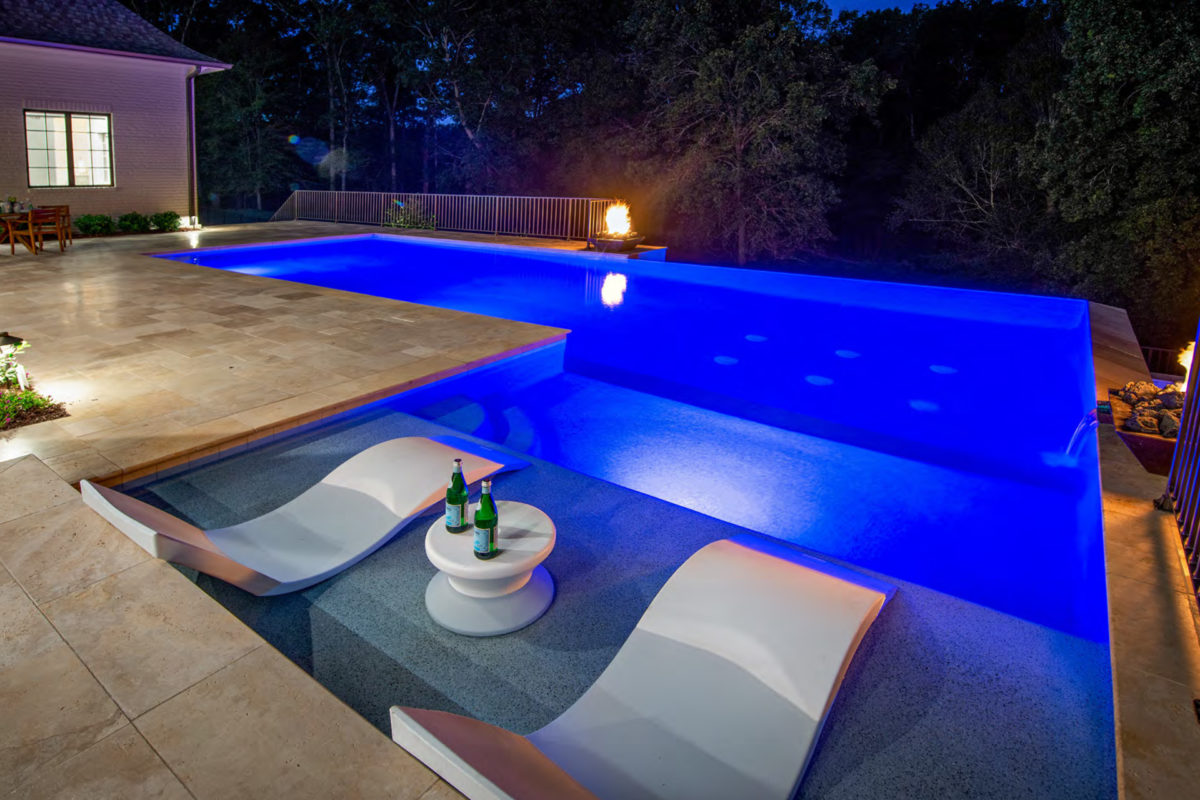 photo of a backyard pool design at nighttime in PebbleTec Blue Lagoon Pool Finish medium blue water color with Fire and Water bowl features for World's Greatest Pools 2019